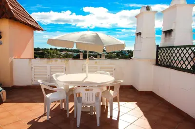 a white table and chairs with an umbrella on a balcony at Two bed Old Village E007 in Vilamoura