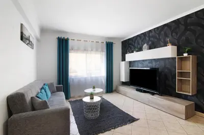 a living room with a couch and a flat screen tv at Apartamento do Sol in Albufeira