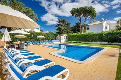 a pool with chairs and an umbrella and a swimming pool at 7 Bedroom Private Villa Tenazinha II, with pool in Albufeira