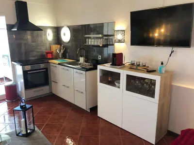 a kitchen with white cabinets and a flat screen tv at Albufeira studio Bellevista in Albufeira