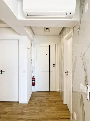 a hallway with white walls and white doors and wood floors at Front Sea Apartment Quarteira in Quarteira