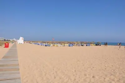 a sandy beach with a pier and a group of people at Marina Vilamoura - Aquamar 402 By Vilamoura Sun in Quarteira
