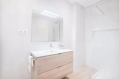 a white bathroom with a sink and a shower at Apartment Tanta - located at the gates of the old in Albufeira