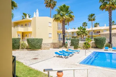 a villa with a swimming pool and palm trees at Apartment Riu - Close to bars shops and restaurants in Albufeira