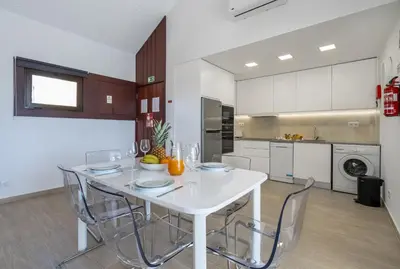 a white kitchen with a white table and chairs at Marina Vision Vilamoura in Vilamoura