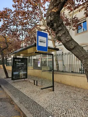 a bus stop with a blue sign next to a tree at Casa Jasmim in Faro