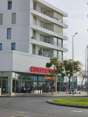 a large white building with people walking in front of it at Casa Jasmim in Faro