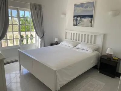 a white bedroom with a large bed and windows at Cabana do Monte in Santa Bárbara de Nexe