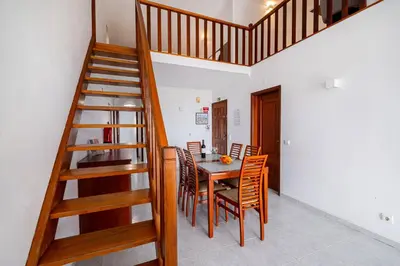 a dining room with a table and chairs and a staircase at Marina Vista Retreat in Albufeira