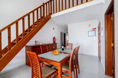 a dining room with a table and chairs and a staircase at Marina Vista Retreat in Albufeira