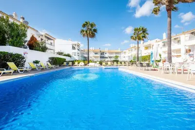 a large swimming pool with chairs and palm trees at Marina Vista Retreat in Albufeira