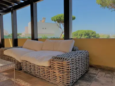 a wicker couch sitting on a porch with windows at Fashion Villa in Vilamoura with Private Pool in Quarteira
