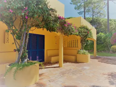 a yellow house with a blue door and some flowers at Fashion Villa in Vilamoura with Private Pool in Quarteira