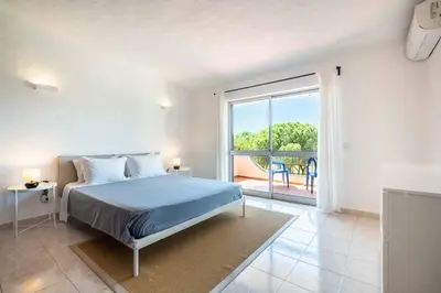 a bedroom with a bed and a large window at Sunny Vilamoura Golf Villa with Private Pool in Quarteira