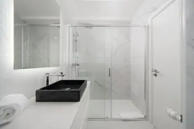 a white bathroom with a shower with a black sink at Villa Olivia in Almancil