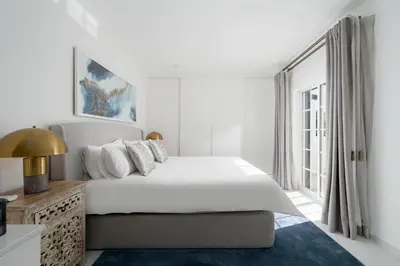 a white bedroom with a large bed and a bathroom at Villa Olivia in Almancil