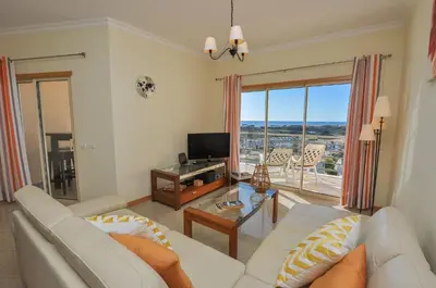 a living room with a white couch and a television at Encosta da Orada by OCvillas in Albufeira