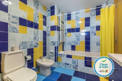 a blue and yellow bathroom with a toilet and a tub at Marina de Albufeira Villa 8 in Albufeira