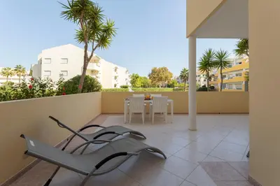 a patio with a chair and a table on a balcony at Centralgarve - Spacious & Elegant - Vilamoura w Pool - Jacarandás in Quarteira