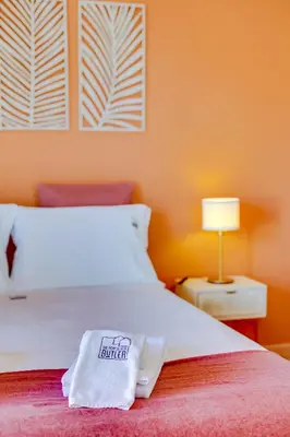 a bedroom with a white bed with an orange wall at Villa Oliveiras de Vilamoura by The Portuguese Butler in Quarteira