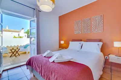 a bedroom with a large bed and a balcony at Villa Oliveiras de Vilamoura by The Portuguese Butler in Quarteira