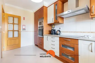 a kitchen with wooden cabinets and a door in a room at #130 Praia Village by Home Holidays in Vilamoura