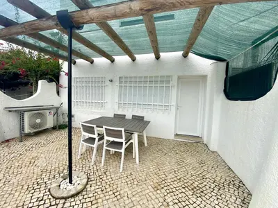 a patio with a table and chairs under a roof at Quarteira Stylish 2 by Homing in Quarteira