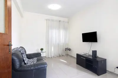 a living room with a black leather chair and a television at Matinhos House in Faro