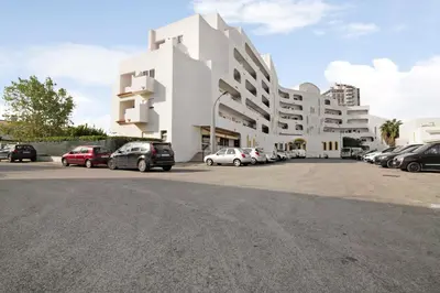 a white building with cars parked in a parking lot at Green 104 in Albufeira