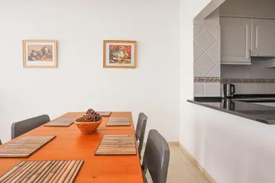 a dining room table with chairs and a kitchen at Apart 2 VelaMar - BY BEDZY in Albufeira