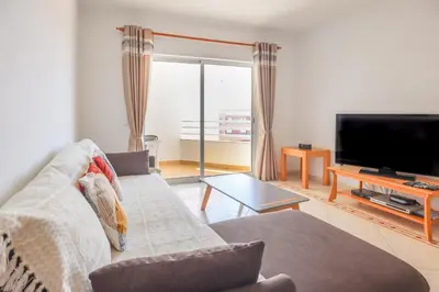 a living room with a couch and a flat screen tv at Apart 2 VelaMar - BY BEDZY in Albufeira