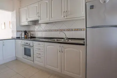 a kitchen with white cabinets and a stainless steel refrigerator at Apart 2 VelaMar - BY BEDZY in Albufeira