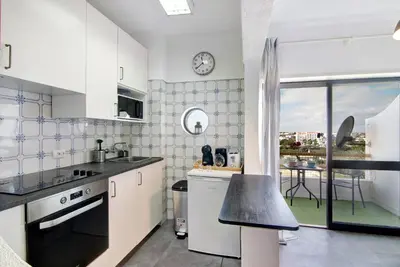 a kitchen with white cabinets and a black counter top at T1 Marques in Albufeira