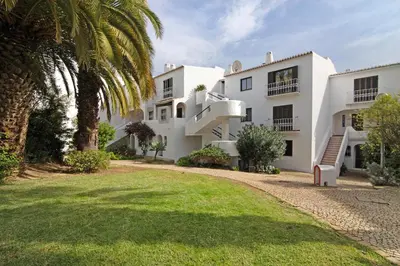 an exterior view of a white building with a palm tree at Flat 2 Bedrooms Cunha in Albufeira