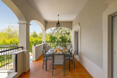 a dining room with a table and chairs on a balcony at Villa Simone in Almancil