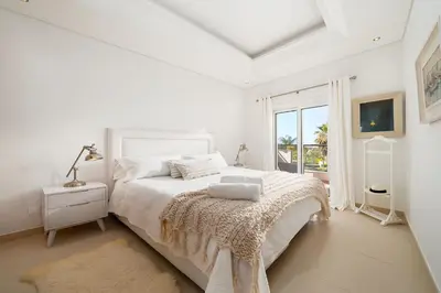 a white bedroom with a bed and a window at Villa Simone in Almancil