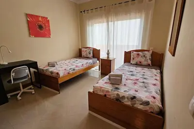 a bedroom with two beds and a desk and a window at D'Água Brisa beachside apartment in Albufeira