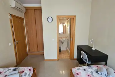 a room with two beds and a desk and a bathroom at D'Água Brisa beachside apartment in Albufeira