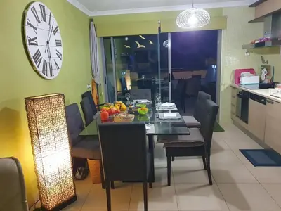 a dining room with a table and a clock on the wall at Magnifique Duplex avec piscine en bord de mer in Olhos de Água