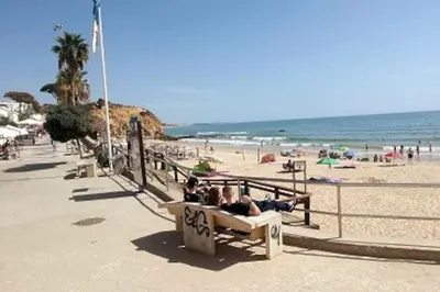a group of people sitting on a bench at the beach at Magnifique Duplex avec piscine en bord de mer in Olhos de Água
