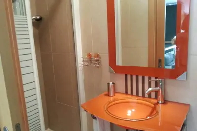 a bathroom with a orange sink and a mirror at Magnifique Duplex avec piscine en bord de mer in Olhos de Água