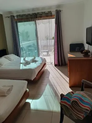a room with two beds and a desk and a television at Magnifique Duplex avec piscine en bord de mer in Olhos de Água