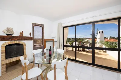 a living room with a fireplace and a glass table and chairs at Villa Veiguinha in Galé