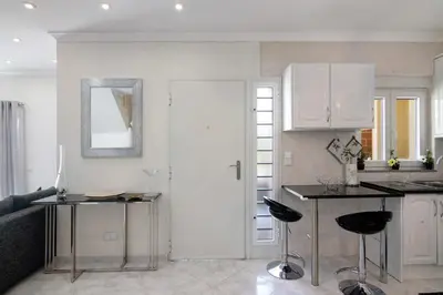 a kitchen with white cabinets and a table and chairs at Vila Alonzo in Albufeira