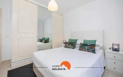 a white bedroom with a bed with a mirror at #195 Rossio Mar by Home Holidays in Albufeira