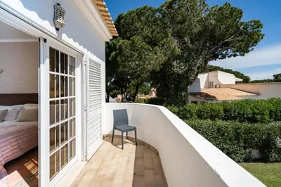 a room with a balcony with a bed and a chair at VTII & VTI 2 X Private Villas with pool and garden in Albufeira