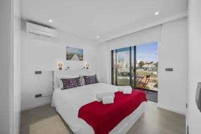a white bedroom with a large bed with a red blanket at Terracos de Quarteira 2 Red by Real Properties in Quarteira