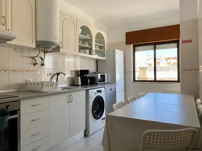 a kitchen with a table and a washing machine at Blife Julya private rooms in Faro