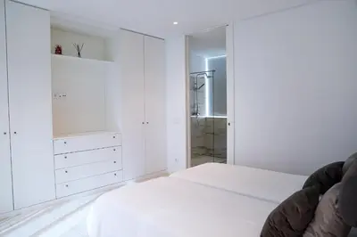 a white bedroom with a bed and a walk in shower at Villa Central By Garvetur in Quarteira