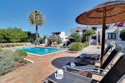 a patio with chairs and an umbrella next to a swimming pool at Quinta Grande de Boliqueime by Portucasa in Boliqueime